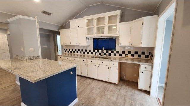 146 Elodie Ave, Harahan, LA 70123 - kitchen featuring a sink, vaulted ceiling, white cabinetry, a peninsula, and decorative backsplash