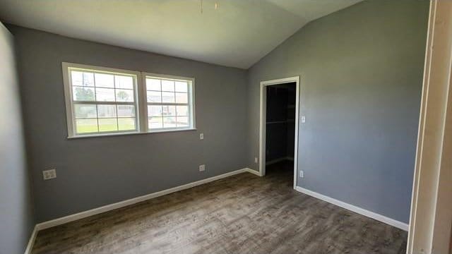 146 Elodie Ave, Harahan, LA 70123 - unfurnished bedroom with vaulted ceiling, baseboards, a walk in closet, a closet, and wood finished floors