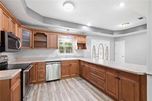 39311 Okefenokee Rd, Pearl River, LA 70452 - kitchen with appliances with stainless steel finishes, a peninsula, light countertops, light wood finished floors, and a sink