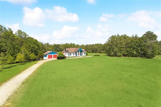 404 Warrior Trce, Covington, LA 70435 - view of front facade featuring dirt driveway, a front yard, a forest view, and a detached garage