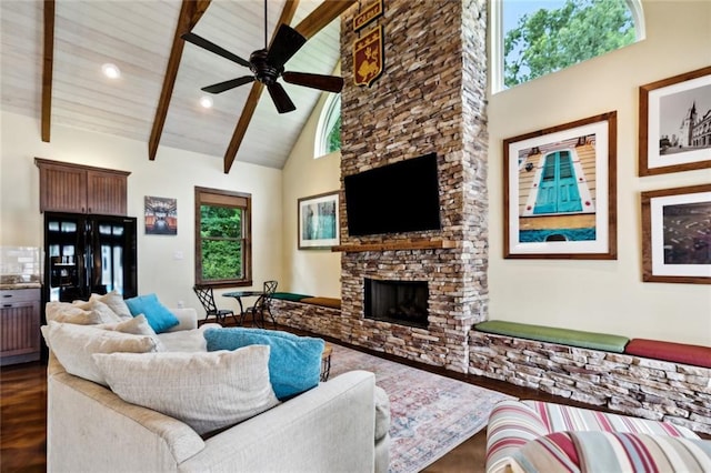42532 S Range Rd, Hammond, LA 70403 - living room featuring dark wood-style flooring, high vaulted ceiling, a stone fireplace, a ceiling fan, and beam ceiling