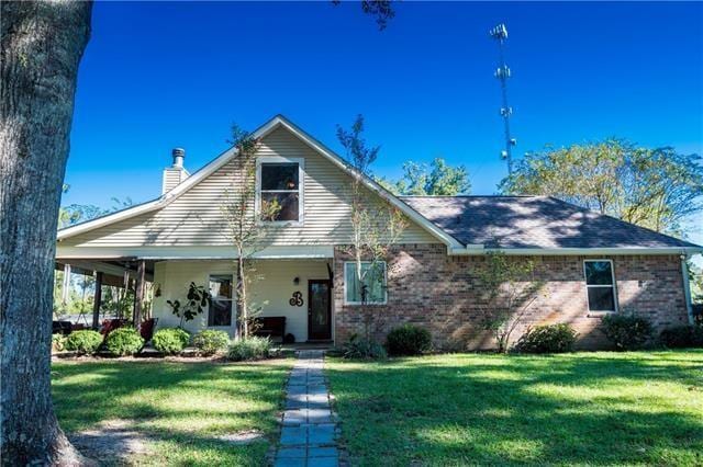 28209 Honey Beagle Ln, Ponchatoula, LA 70454 - view of front facade featuring a chimney, a front yard, brick siding, and covered porch