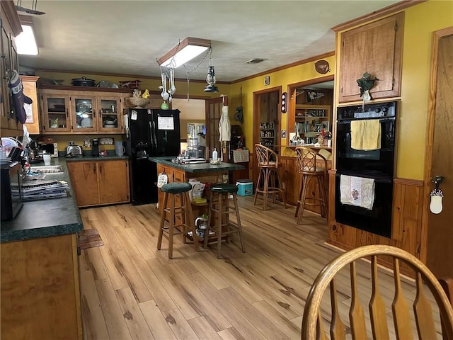 30010 River Rd, Mount Hermon, LA 70450 - kitchen with black appliances, dark countertops, brown cabinetry, light wood-style floors, and a kitchen island