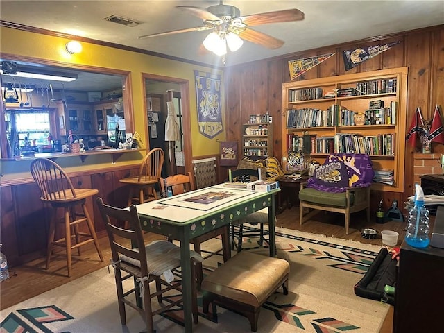 30010 River Rd, Mount Hermon, LA 70450 - dining room featuring wood walls, a ceiling fan, a dry bar, wood finished floors, and crown molding