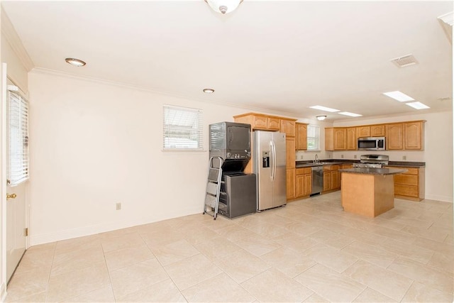 2904 Lloyds Ave, Chalmette, LA 70043 - kitchen featuring stainless steel appliances, dark countertops, crown molding, plenty of natural light, and a kitchen island