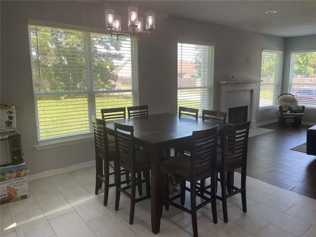 2133 Wellington Ln, Slidell, LA 70461 - dining room with a chandelier, baseboards, a fireplace with flush hearth, and light tile patterned floors