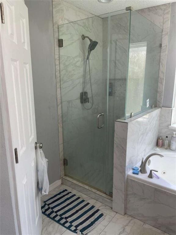 2133 Wellington Ln, Slidell, LA 70461 - full bathroom with marble look tile flooring, a shower stall, a tub with jets, and a textured ceiling