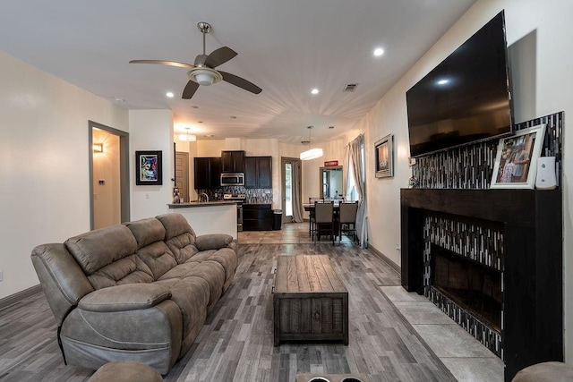 136 Oak Leaf Dr, Slidell, LA 70461 - living room with a tile fireplace, a ceiling fan, recessed lighting, wood finished floors, and baseboards