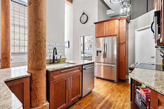 920 Poeyfarre St Unit 176, New Orleans, LA 70130 - kitchen with appliances with stainless steel finishes, a high ceiling, light stone counters, light wood-style flooring, and brown cabinetry