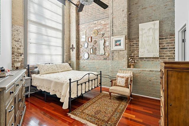 920 Poeyfarre St Unit 176, New Orleans, LA 70130 - bedroom with brick wall, dark wood finished floors, and a towering ceiling