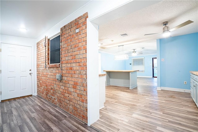 131 Ann St, Saint Rose, LA 70087 - hall featuring brick wall, wood finished floors, baseboards, and a textured ceiling