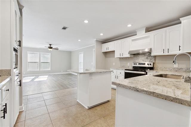 15 E Chalmette Cir, Chalmette, LA 70043 - kitchen with stainless steel range with electric stovetop, under cabinet range hood, a sink, ceiling fan, and light tile patterned flooring