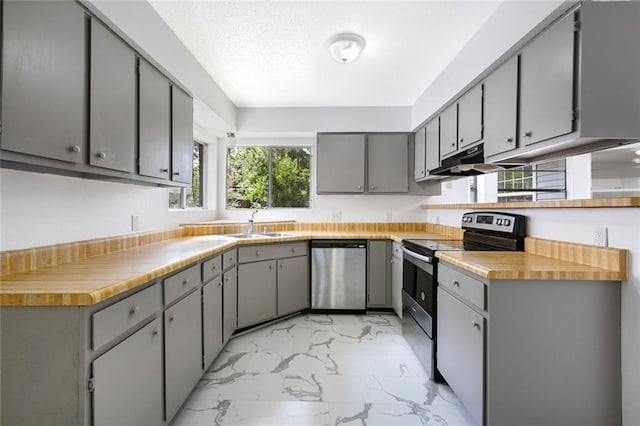 415 Ridgewood Dr, Mandeville, LA 70471 - kitchen with appliances with stainless steel finishes, light marble finish flooring, gray cabinets, under cabinet range hood, and light countertops