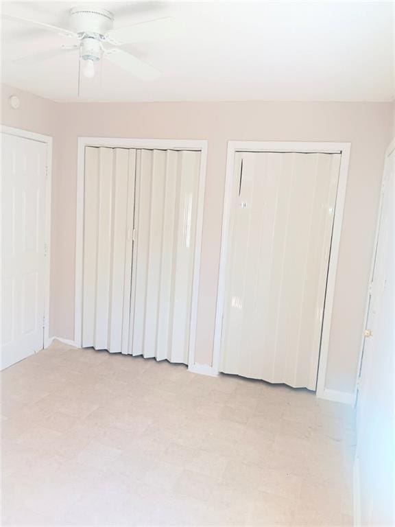 1938 Longwood Ct, La Place, LA 70068 - unfurnished bedroom featuring two closets, baseboards, and a ceiling fan