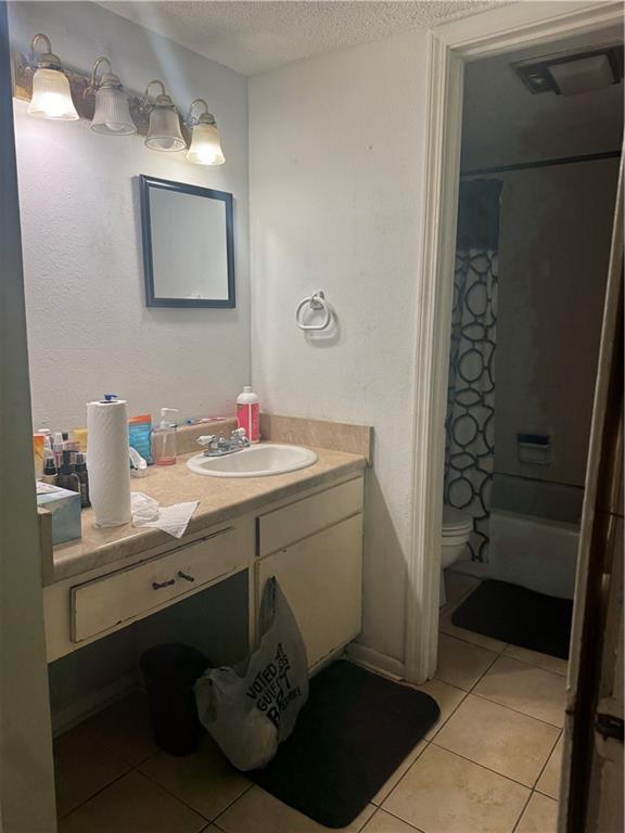6220 Riverside Dr Unit 556, Metairie, LA 70003 - bathroom with vanity, a textured ceiling, tile patterned floors, toilet, and shower / bath combo with shower curtain