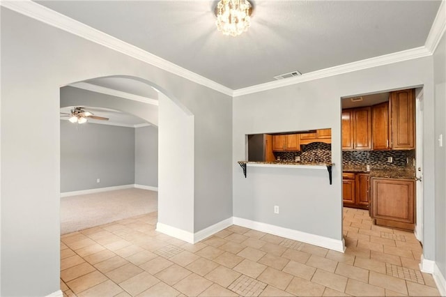 1900 Woods Dr, Metairie, LA 70001 - kitchen featuring arched walkways, brown cabinets, ornamental molding, ceiling fan, and tasteful backsplash