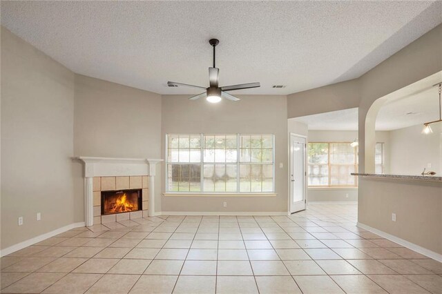 1556 Cherry St, Slidell, LA 70460 - unfurnished living room with a ceiling fan, a fireplace, a textured ceiling, light tile patterned floors, and baseboards