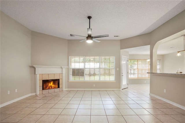 1556 Cherry St, Slidell, LA 70460 - unfurnished living room with a ceiling fan, a fireplace, a textured ceiling, light tile patterned floors, and baseboards