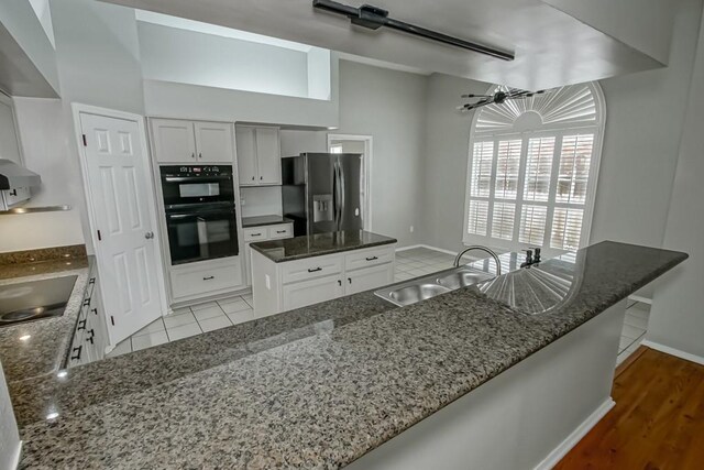 1550 De Battista Pl, New Orleans, LA 70131 - kitchen featuring black appliances, a sink, dark stone countertops, white cabinetry, and a peninsula