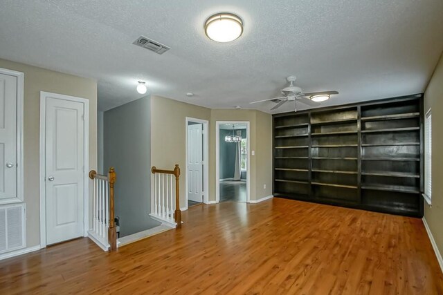 1550 De Battista Pl, New Orleans, LA 70131 - unfurnished room featuring a textured ceiling, baseboards, wood finished floors, a ceiling fan, and built in features