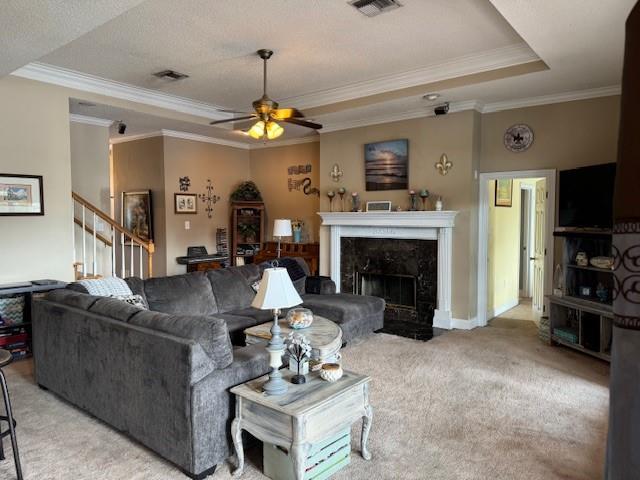 203 Lorelei Cir, Slidell, LA 70458 - living room featuring a raised ceiling, light colored carpet, a ceiling fan, a premium fireplace, and crown molding