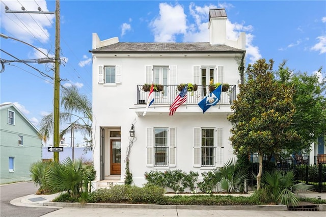 2538 N Rampart St, New Orleans, LA 70117 - view of front of property with a balcony, a chimney, and stucco siding