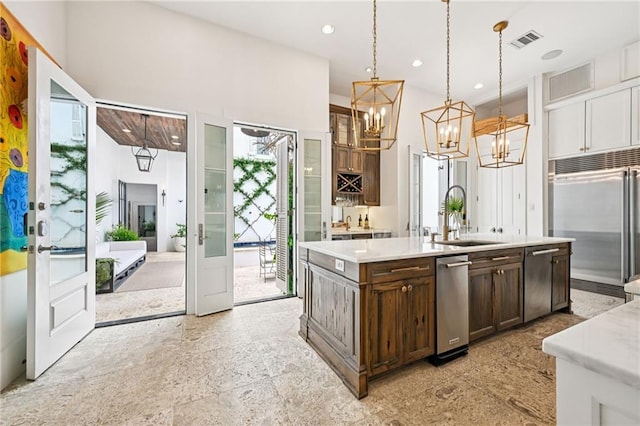 2538 N Rampart St, New Orleans, LA 70117 - kitchen with appliances with stainless steel finishes, a chandelier, light countertops, a center island with sink, and dark brown cabinets