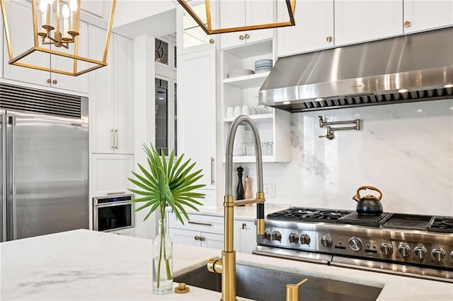 2538 N Rampart St, New Orleans, LA 70117 - kitchen featuring under cabinet range hood, appliances with stainless steel finishes, white cabinets, and light stone countertops