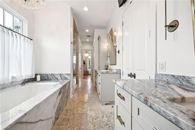 2538 N Rampart St, New Orleans, LA 70117 - full bathroom with two vanities, recessed lighting, a bath, a chandelier, and stone finish floors