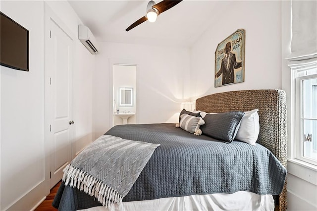 2538 N Rampart St, New Orleans, LA 70117 - bedroom with a wall mounted AC, wood finished floors, a ceiling fan, and connected bathroom