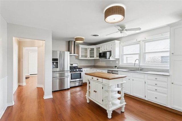 725 N Turnbull Dr, Metairie, LA 70001 - kitchen featuring stainless steel appliances, a sink, wall chimney exhaust hood, butcher block counters, and white cabinetry