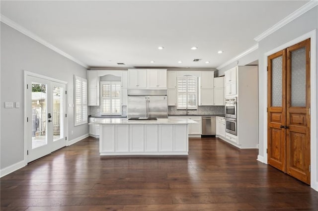 5830 Marshal Foch St, New Orleans, LA 70124 - kitchen with stainless steel appliances, crown molding, white cabinetry, dark wood finished floors, and a center island