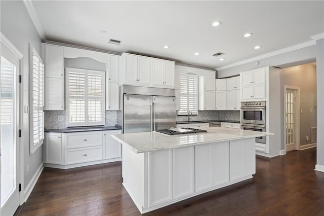 5830 Marshal Foch St, New Orleans, LA 70124 - kitchen featuring appliances with stainless steel finishes, a sink, crown molding, white cabinets, and dark wood-type flooring
