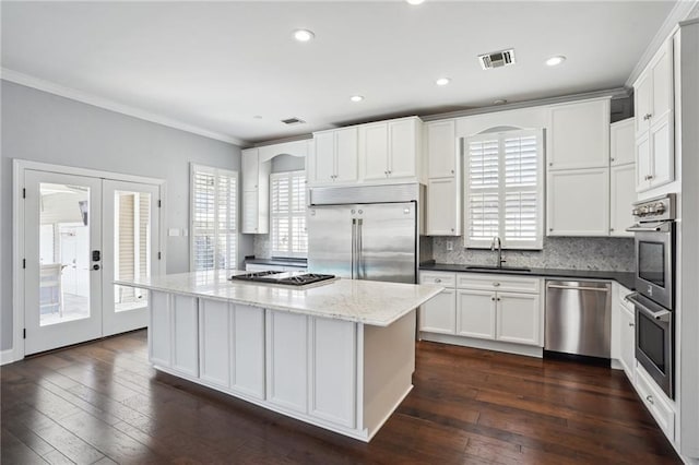 5830 Marshal Foch St, New Orleans, LA 70124 - kitchen featuring stainless steel appliances, a sink, crown molding, backsplash, and dark wood-style floors