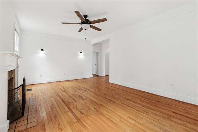 5524 S Galvez St, New Orleans, LA 70125 - unfurnished living room with ceiling fan, light wood-type flooring, a fireplace with raised hearth, and baseboards