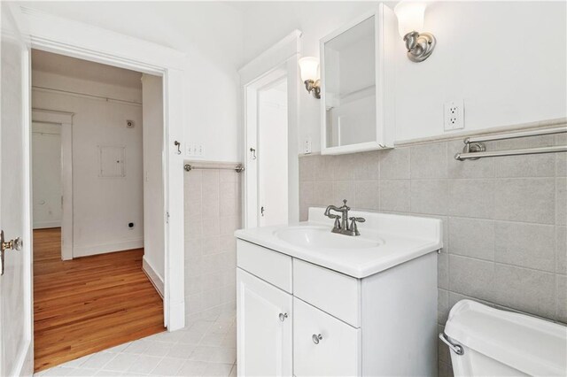 5524 S Galvez St, New Orleans, LA 70125 - half bath with tile walls, vanity, toilet, wood finished floors, and a wainscoted wall