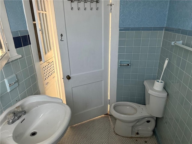 3526 Louisiana Ave Parkway, New Orleans, LA 70125 - bathroom with a sink, tile walls, toilet, tile patterned flooring, and a wainscoted wall