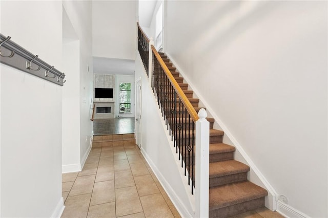 103 Catalpa Ln Unit 231, Mandeville, LA 70471 - stairs with a large fireplace, baseboards, tile patterned floors, and a high ceiling