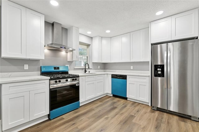 38 Gretna Blvd, Gretna, LA 70053 - kitchen featuring stainless steel appliances, wall chimney range hood, a sink, white cabinetry, and light wood-style floors