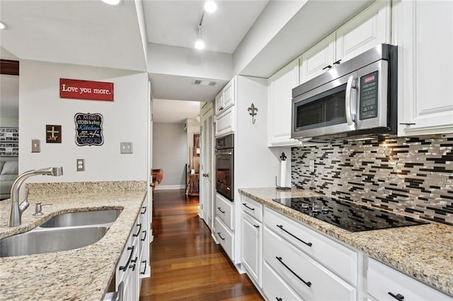 585 Beau Chene Dr, Mandeville, LA 70471 - kitchen featuring stainless steel microwave, a sink, black electric stovetop, oven, and backsplash