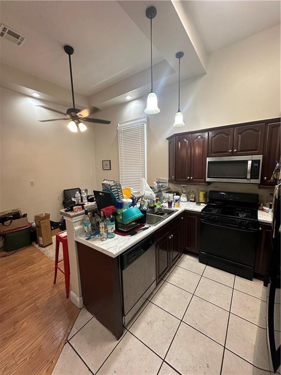 33537 Elmira Ave, New Orleans, LA 70114 - kitchen featuring stainless steel microwave, black gas range oven, dishwashing machine, light countertops, and a sink