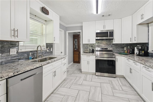 2018 Old River Rd, Slidell, LA 70461 - kitchen featuring stainless steel appliances, a sink, tasteful backsplash, white cabinets, and a textured ceiling