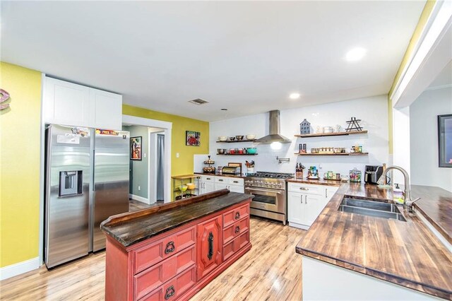 123 Willow Ct, Raceland, LA 70394 - kitchen with stainless steel appliances, open shelves, a sink, wall chimney exhaust hood, and light wood-style flooring
