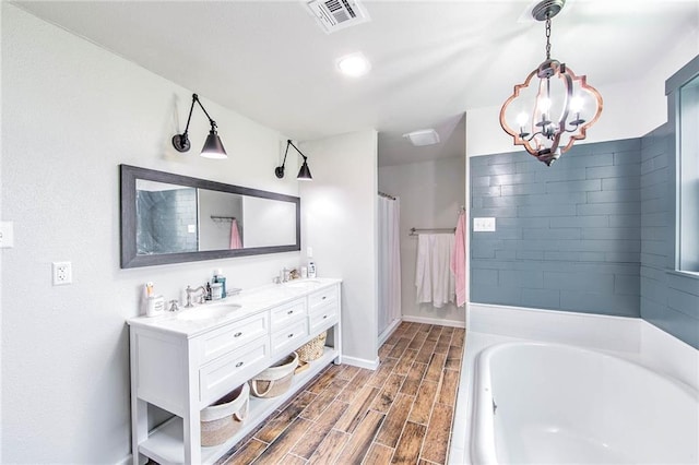 123 Willow Ct, Raceland, LA 70394 - full bathroom featuring double vanity, a garden tub, a chandelier, wood finished floors, and baseboards