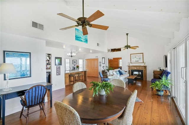 329 Carr Dr, Slidell, LA 70458 - dining area featuring a glass covered fireplace, ceiling fan, wood-type flooring, a chandelier, and high vaulted ceiling