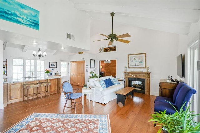 329 Carr Dr, Slidell, LA 70458 - living area featuring a chandelier, light wood finished floors, a fireplace, beam ceiling, and a ceiling fan