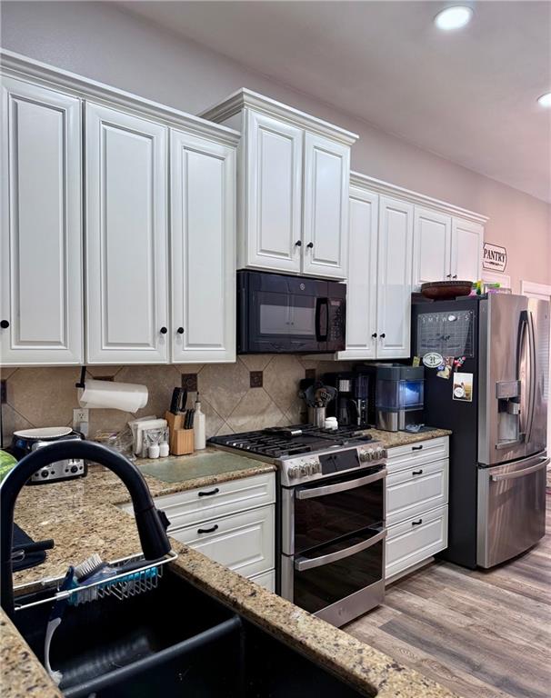 246 Betty Dr, Montz, LA 70068 - kitchen featuring stainless steel appliances, white cabinets, light wood-style flooring, tasteful backsplash, and recessed lighting