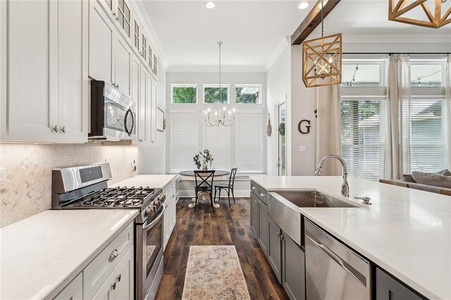 668 Highlands Dr, Slidell, LA 70458 - kitchen featuring stainless steel appliances, a sink, a chandelier, crown molding, and dark wood finished floors