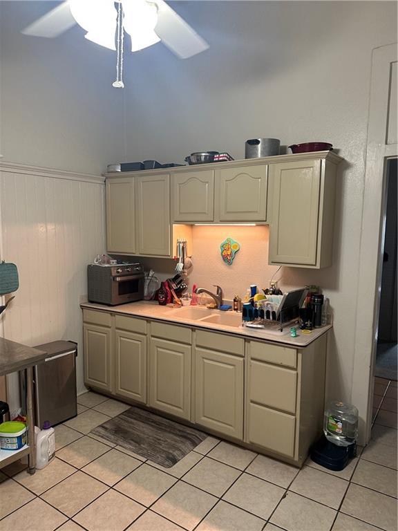 70911 Evelina St, New Orleans, LA 70114 - kitchen with light tile patterned flooring, light countertops, ceiling fan, a sink, and a wainscoted wall