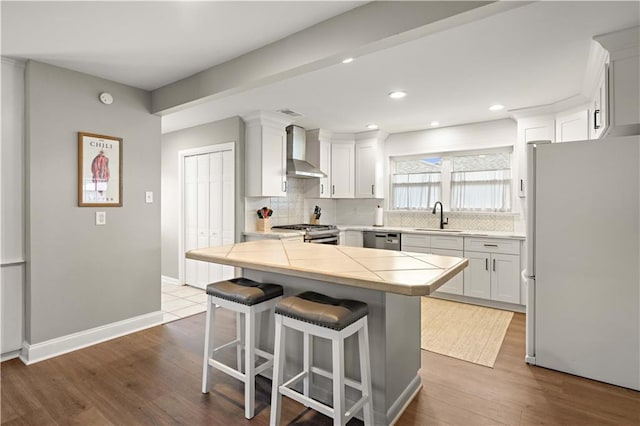 1924 Cammie Ave, Metairie, LA 70003 - kitchen featuring stainless steel appliances, wall chimney exhaust hood, decorative backsplash, a kitchen breakfast bar, and recessed lighting